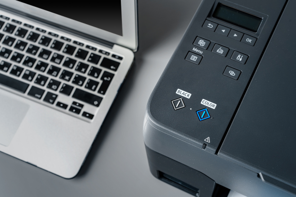 Laptop mit FaxSuite-Oberfläche neben Drucker – digitale Faxlösung im Büroalltag